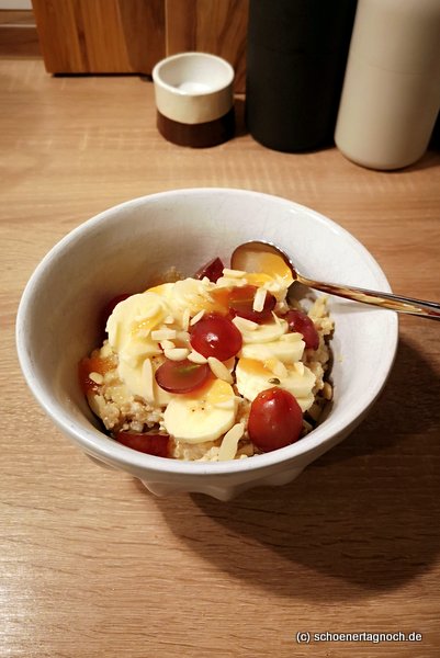 Quinoa-Porridge mit Mandelmilch, Bananen, Weintrauben, Mandelstiften und Honig