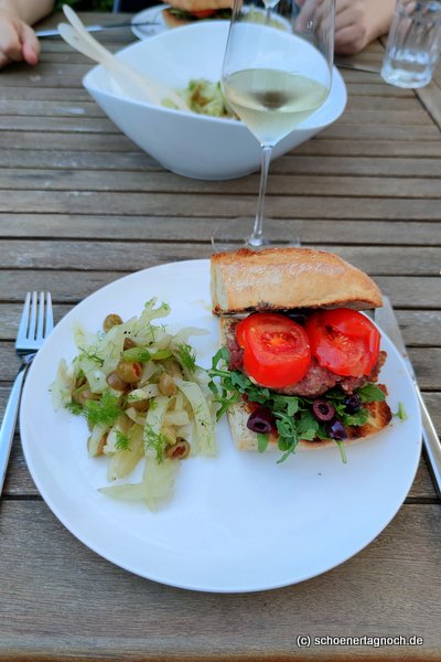 "The Italian Burger" vom Grill mit Salsiccia, Rucola und Tomatenpesto, dazu Fenchel-Oliven-Salat